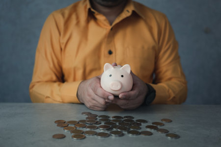 Man hand holding piggy bank with many coin on the table. Saving money wealth and financial concept, investment and planning money.の写真素材