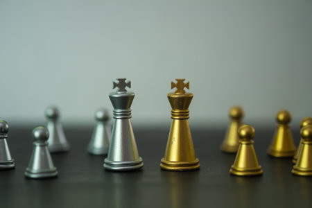 A golden king chess piece and a silver king chess piece are standing together. Leadership,...