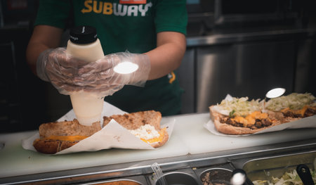 Bangkok, Thailand - February 16, 2023 : Subway staff is cooking sandwich at Subway shop in Thailand. Subway is an American fast food restaurant franchise that sells sandwiches and salads.のeditorial素材
