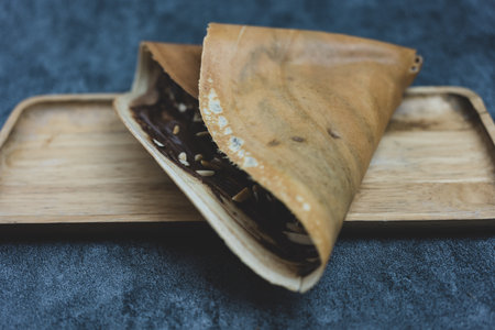 Crispy crepe with cocoa sauce and sliced roasted almond served on wood tray.の写真素材