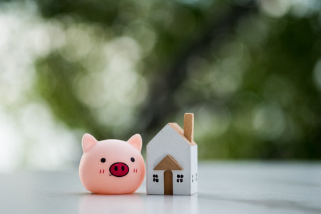 Happy life in the home concept. Enjoying life concept. positive mind. Miniature wood home and cute toy pig against blur nature backgroundの写真素材