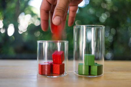 Hand putting a red wooden block in a glass against nature background. Concept of vote