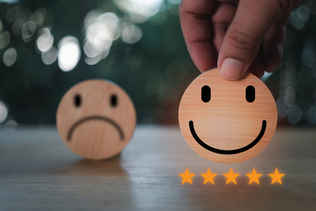 Hand picking happy smiley face icon on circular wooden block, Rating satisfaction five stars, Evaluating best service to customers, Customer service and satisfaction survey concept. Service rating.の写真素材