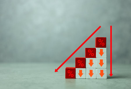 Red wooden cubes with icon percentage above arrow pointing down. The direction of an arrow symbolizing that the interest rates are going down. Financial concept and copy spaceの写真素材