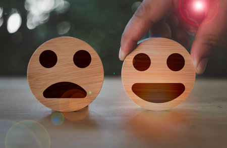 Hand of the customer picking happy face for rate service or products. Wooden circle for positive mindset selection and marketing customer satisfaction review concept. Satisfaction survey concept.の写真素材