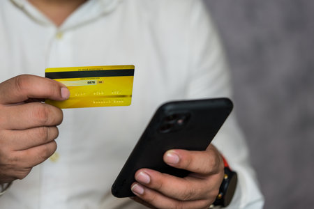 Man in white shirt use mobile cell phone credit bank card shopping. Online payment concept. Entering information, shopping, ordering in internet store, doing secure paymentの写真素材