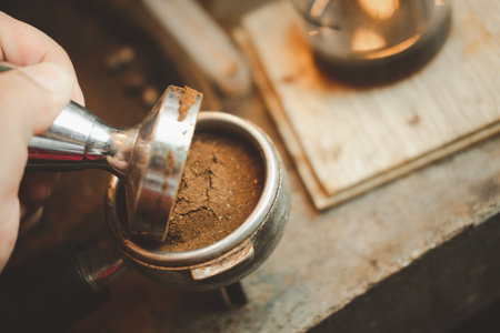 Barista using a tamper to press ground coffee into a portafilter. Close upの写真素材