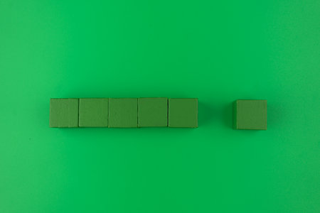 Green wooden cubes stacked over green background. Top viewの写真素材