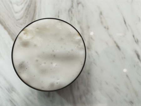 Directly above shot of fresh milk foam in glass on a white marble backgroundの写真素材