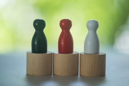 Three colour of wooden peg dolls on wood block on a nature background. Close upの写真素材