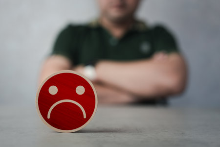 Customer experience dissatisfied. Unhappy man client crossed arms and feedback sadness emotion face on wood block. Bad rating and negative reviews and customer experience dissatisfaction.の写真素材