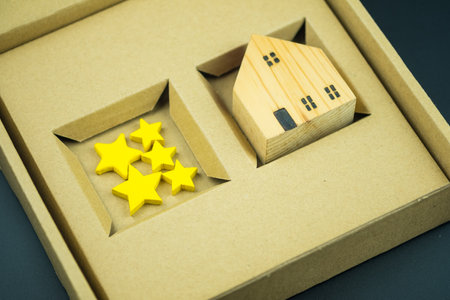 Five star rating for house. Wood home model and yellow star on brown paper box or business real...