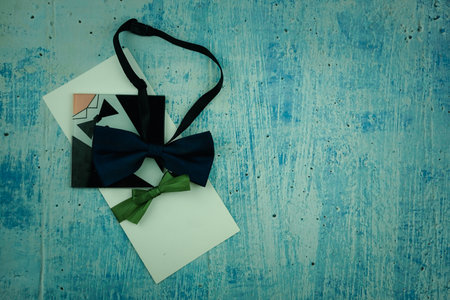 Card invitation wedding and dark blue bow tie top view on a blue background. Wedding invitation set. space for textの写真素材