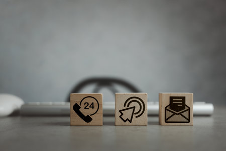 Contact Us icons on wooden blocks with the keyboard on a wooden desk. Contact us about the concept of customer service center connection. Communication on the Internet through the websiteの写真素材