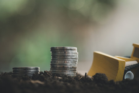 The stacked coin on soil and grader car for background concept in grow money for success in business and deposit interest from savingの写真素材