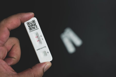 Man holding Rapid Antigen Test kit with Positive result during swab COVID-19 testing. Coronavirus...