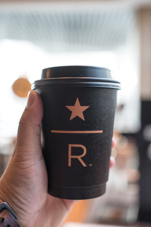 Samut Prakan, Thailand - May 19, 2023 : Man holding hot coffee at at Starbucks Reserve, Mega Bangnashopping mall. Starbucks corporation is an American coffee company and coffeehouse chain.のeditorial素材