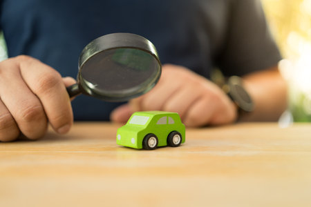 Hand with a black magnifying glass searching for a car to rent or buy. The concept of selection a carの写真素材