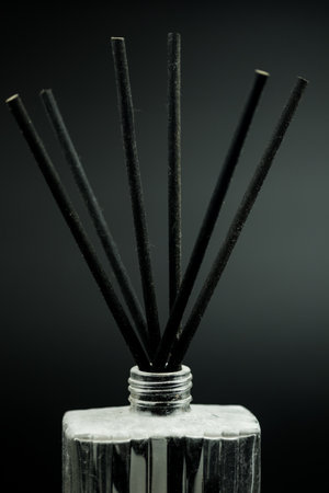 Vertical shot of an air refresher bottle with aromatic black sticks on a black background. Spa conceptの写真素材