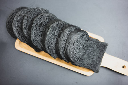 Black charcoal toast bread on wood tray.の写真素材