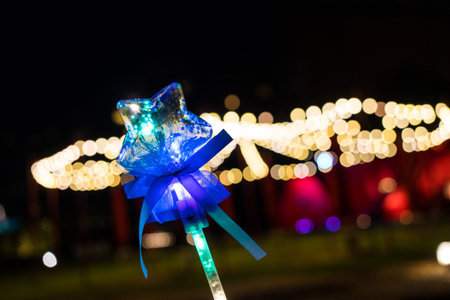 Colorful star shape light stick in hand with light on a bokeh background. Close upの写真素材