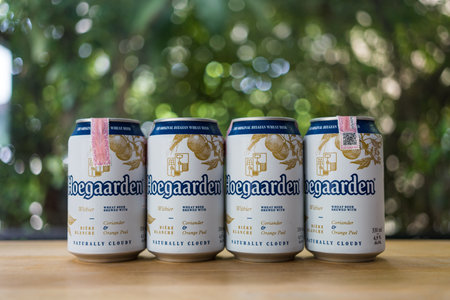 Bangkok, Thailand - July 4, 2023 : A group Hoegaarden wheat beer in can 330ml on wood table. Selective focusのeditorial素材