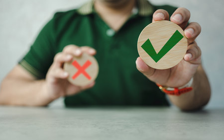 Wooden blocks show the right check marks and are wrong by hand man, decisions and thinking. Approval theme. Concept of choice yes on wooden blocks.の写真素材