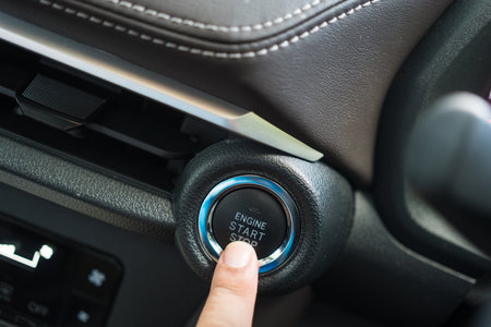 Pressing engine start stop button of a car. Close up