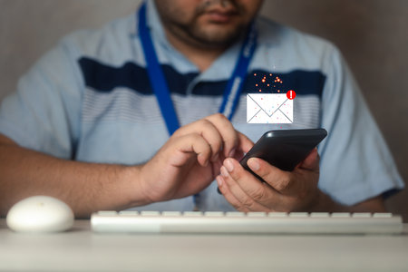 Man hand using smartphone on the table at the office with email icon flying. Responding to emails....