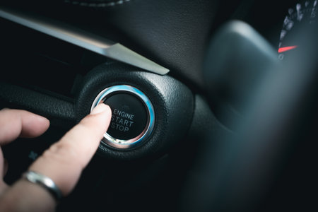 Finger pressing the engine start stop button of a car. Close up