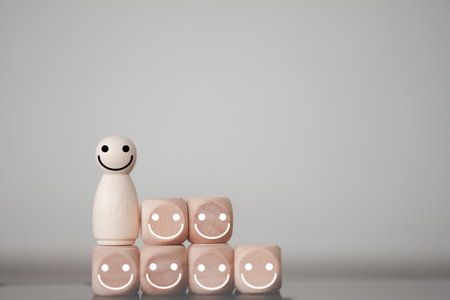 Happy wooden human figure peg dolls with many smile icons on wooden cubes. Concept of family mental health, international day of families.の写真素材