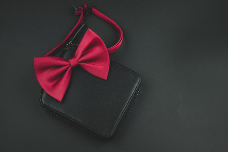 Male red bow tie and black leather wallet on a black background. Men apparel style conceptの写真素材