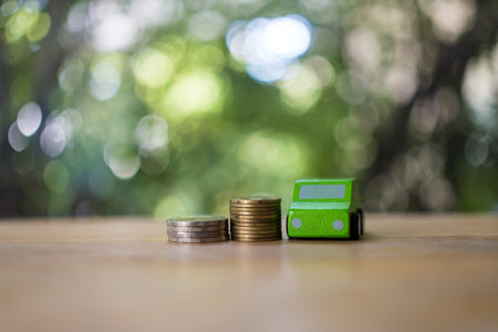 Green car model toy and coin of pile with blurred background, concept of car finance, insurance and travel related issue.の写真素材