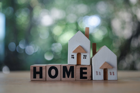 Wooden blocks wording HOME and two small house models against natural background. Concept of property investment and real estate, environmentally friendly building.の写真素材
