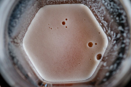 Beer with bubble foam on glass, top view
