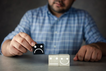 The customer hand picked and choosed a sad face icon on the black wood cube. Customer review experience dissatisfied choosing bad rating review Negative idea of unhappy, poor service or poor qualityの写真素材