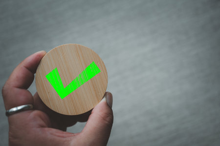 Close up green check mark icon on round wood, chosen green check mark by business's hand. Picking...
