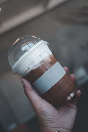 Close up man hand holding takeaway plastic cup of delicious iced Mocha coffee