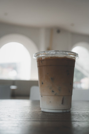 A glass of iced latte coffee served on the wooden table in a coffee shop. Close upの写真素材