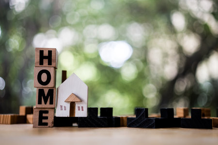 A model house model with text of HOME is placed on wood table as background property real estate...