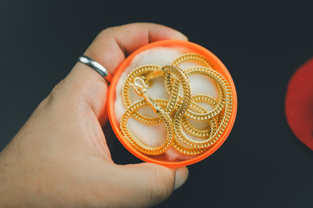 Gold necklace in a red box in the shape of a round in hand. Designer thick gold curb link for men