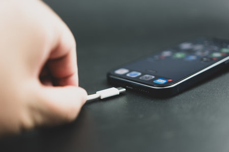 Bangkok, Thailand - October 27, 2023 : Close up of man connects usb type-c cable to iPhone 15 Pro blue Titanium. Type C wired Charger.のeditorial素材