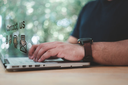 Man working on laptop on a table with nature background and connection about customer support hotline contact us. Searching Customer support hotline. Web page online customer service technology idea.の写真素材