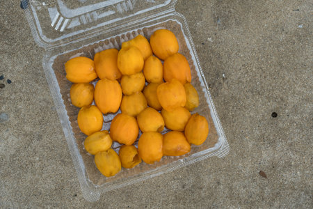 Peel of fresh maprang, is a popular tropical fruit in Thailand, fresh yellow-orange flesh is peeled...