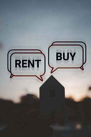 Hand holding wooden home with text message Buy or Rent against sunset background. Real estate concept, making decisionの写真素材