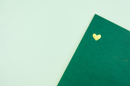 Golden alone heart on green paper notebook with copy space. Love and Happy Valentine day conceptの写真素材