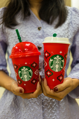 Bangkok, Thailand - November 21, 2023: Two Christmas Reusable Cups for hot and iced drinks when purchasing a beverage 16 oz. or above. Starbucks coffee drink in the 2023 designed red cup for Christmasのeditorial素材