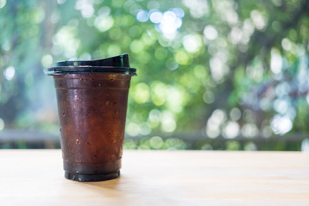 Closeup shot of a plastic glass of black coffee on wood tableの写真素材