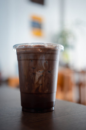 Iced refreshing a black mocha in glass placed on a wooden table at a cafe. Close upの写真素材