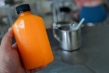 Male hand holding plastic bottles with orange juice. Orange juice for healthy dayの写真素材